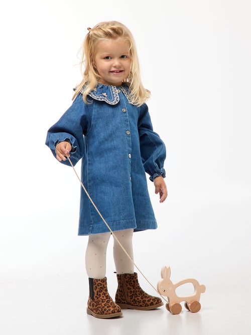 Robe-chemise enfant en denim bleu durable, avec boutons blancs et grand col rond brodé de motifs floraux, fabriquée en coton bio et matières recyclées.