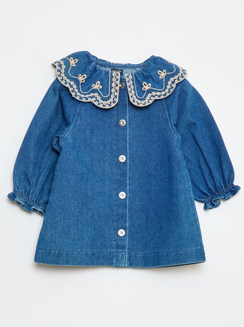 Robe-chemise enfant en denim bleu durable, avec boutons blancs et grand col rond brodé de motifs floraux, fabriquée en coton bio et matières recyclées.