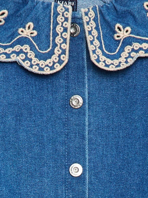 Robe-chemise enfant en denim bleu durable, avec boutons blancs et grand col rond brodé de motifs floraux, fabriquée en coton bio et matières recyclées.